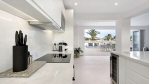 Cozinha moderna com bancada de mármore, fogão embutido e vista para o pátio externo.