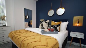 Une chambre à coucher comprenant un lit, des tables de chevet, une commode, un miroir et des lampes fixées au mur.