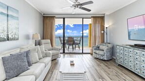 A spacious living room with a sofa, coffee table, and a view of the ocean through large windows. - Summer House 1105A (Orange Beach)