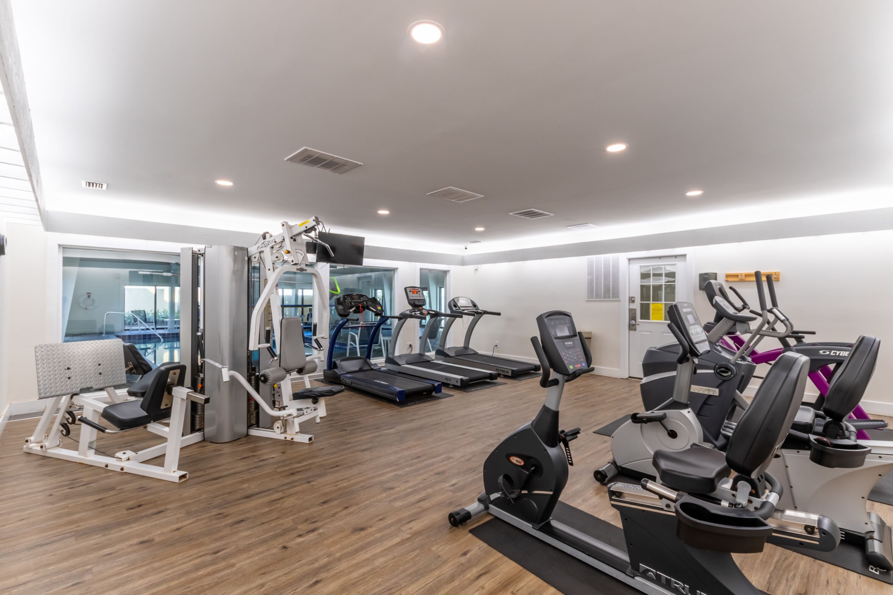 A modern gym with treadmills, elliptical machines, and weight equipment.