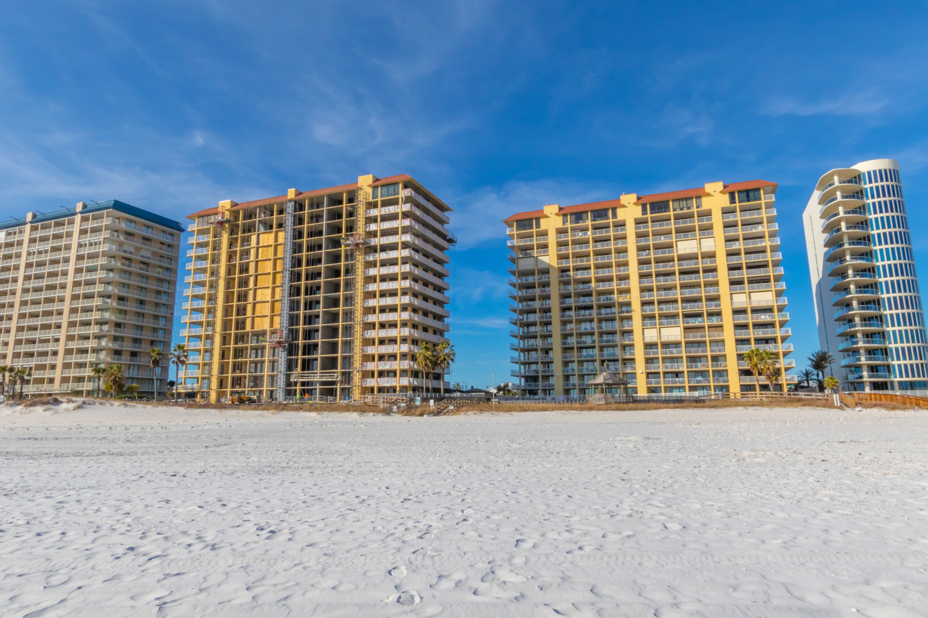 Een strandhotel met meerdere hoge gebouwen, een zandstrand en palmbomen.