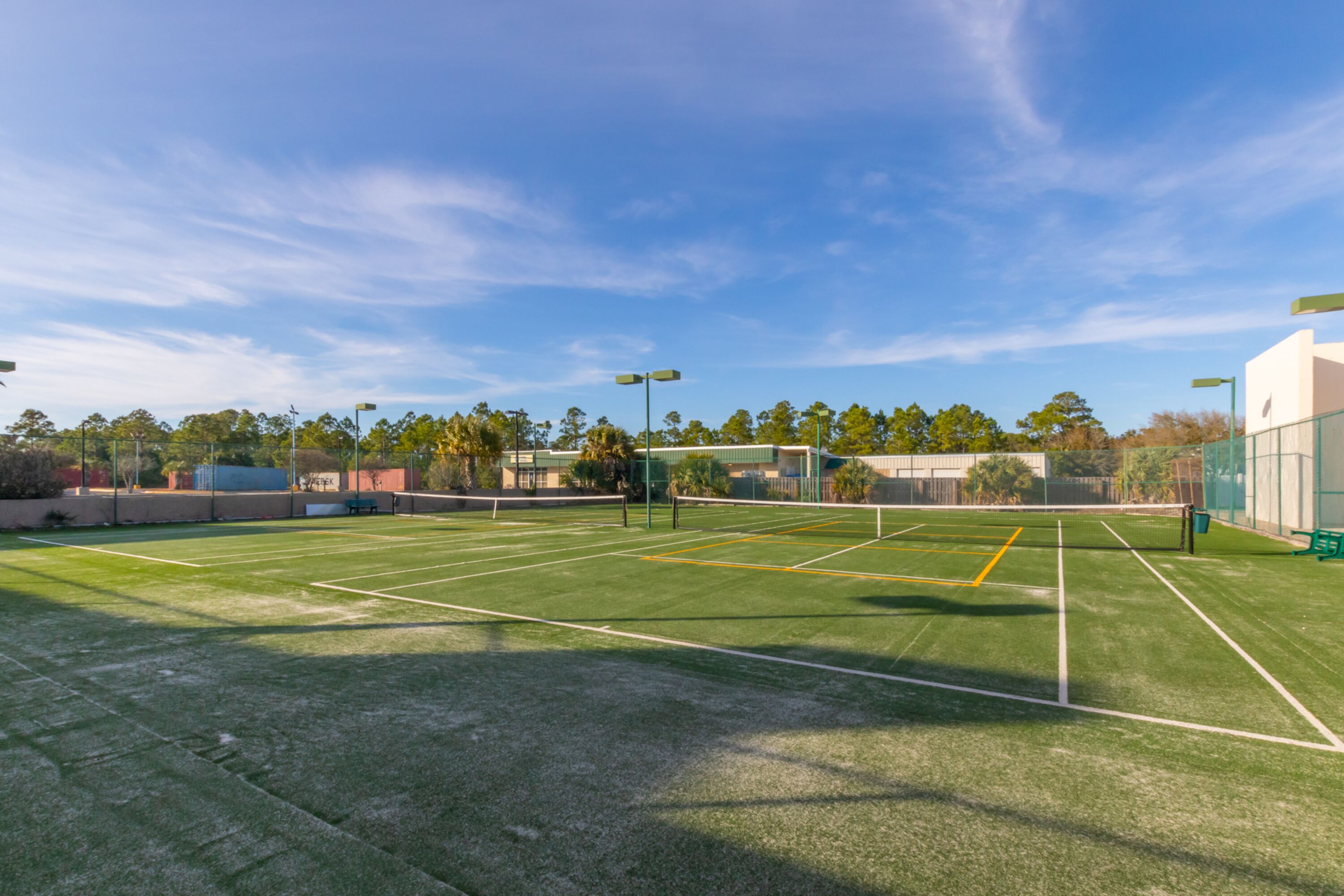 A tennis court with clear lines, surrounded by trees and buildings.