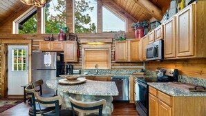 A kitchen with wooden cabinets, granite countertops, and a stone island with bar stools.