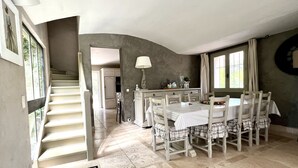 A dining area with a round table, chairs, and a staircase leading to another room. - Villa Maya : Large villa and amazing pool in Luberon (Mérindol)