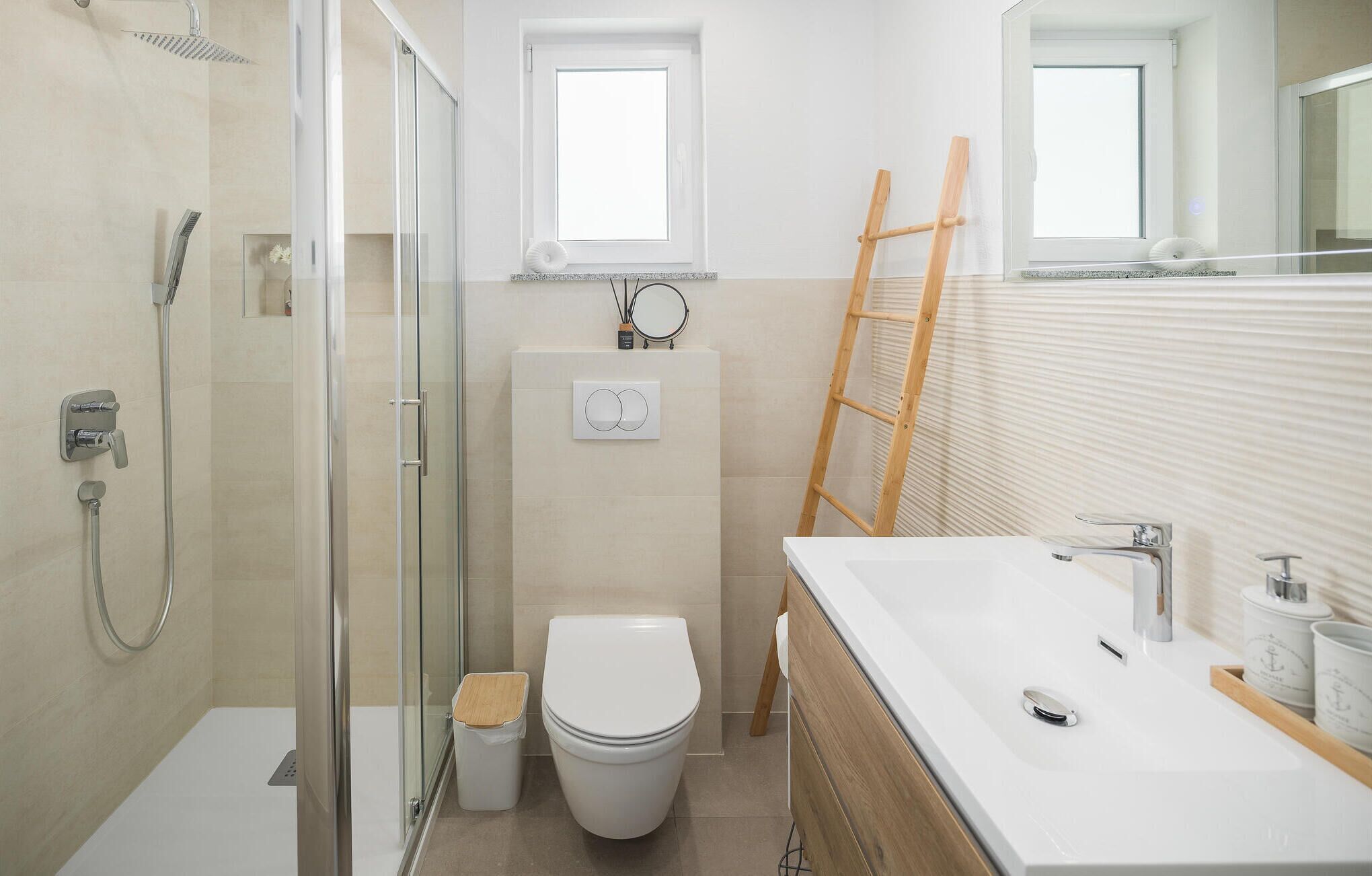 Ein modernes Badezimmer mit Duschkabine aus Glas, Toilette und Waschtisch mit Spüle und Spiegel.
