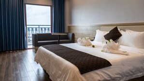 A hotel room with a large bed, a sofa, and a view of the city through a balcony. - G.C Royal Hotel (Accra)