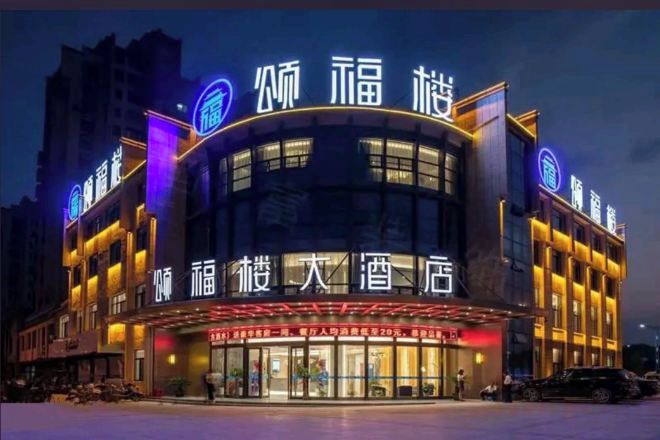 A hotel with a curved facade, illuminated signage, and a large entrance.