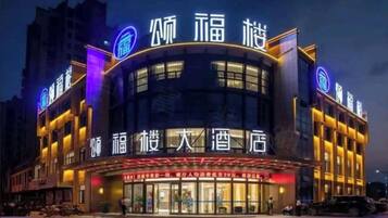 A hotel with a curved facade, illuminated signage, and a large entrance.