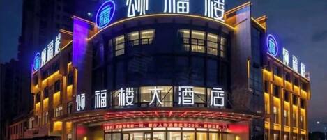 Un hôtel doté d’une façade incurvée, d’une enseigne lumineuse et d’une grande entrée.
