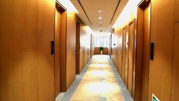 A hotel corridor with wooden doors, a patterned carpet, and a green emergency exit sign.