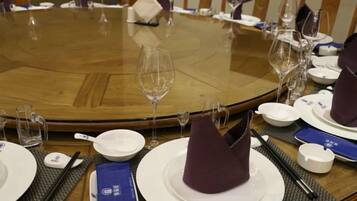 A round dining table with plates, glasses, and cutlery.