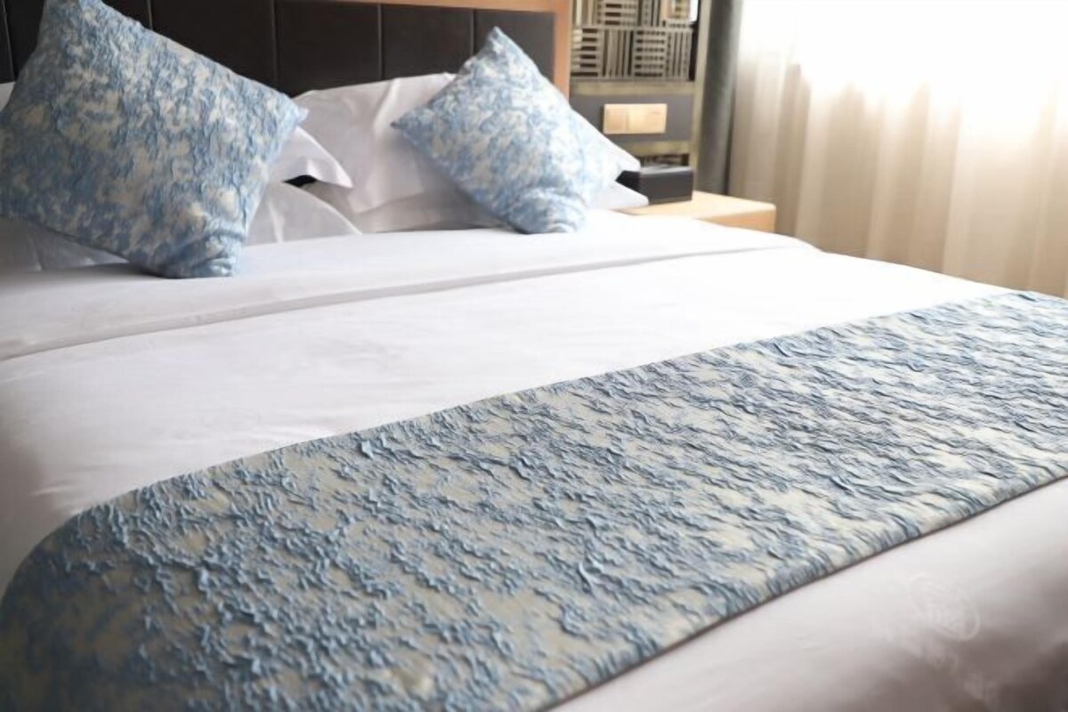 A neatly made bed with a patterned bedspread and two pillows.