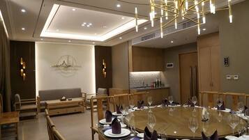 A modern dining area with a round table set for a meal, a sofa, and a kitchen area in the background.