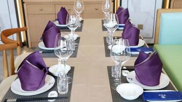A dining table set with plates, glasses, and purple napkins.