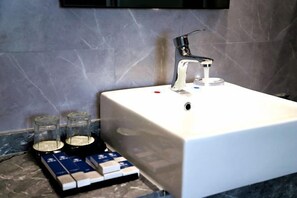 A bathroom with a white sink, a modern faucet, and a marble wall. - Songfulou Hotel (Qimen)