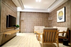 A modern living room with a flat-screen TV, wooden furniture, and a painting on the wall. - Songfulou Hotel (Qimen)