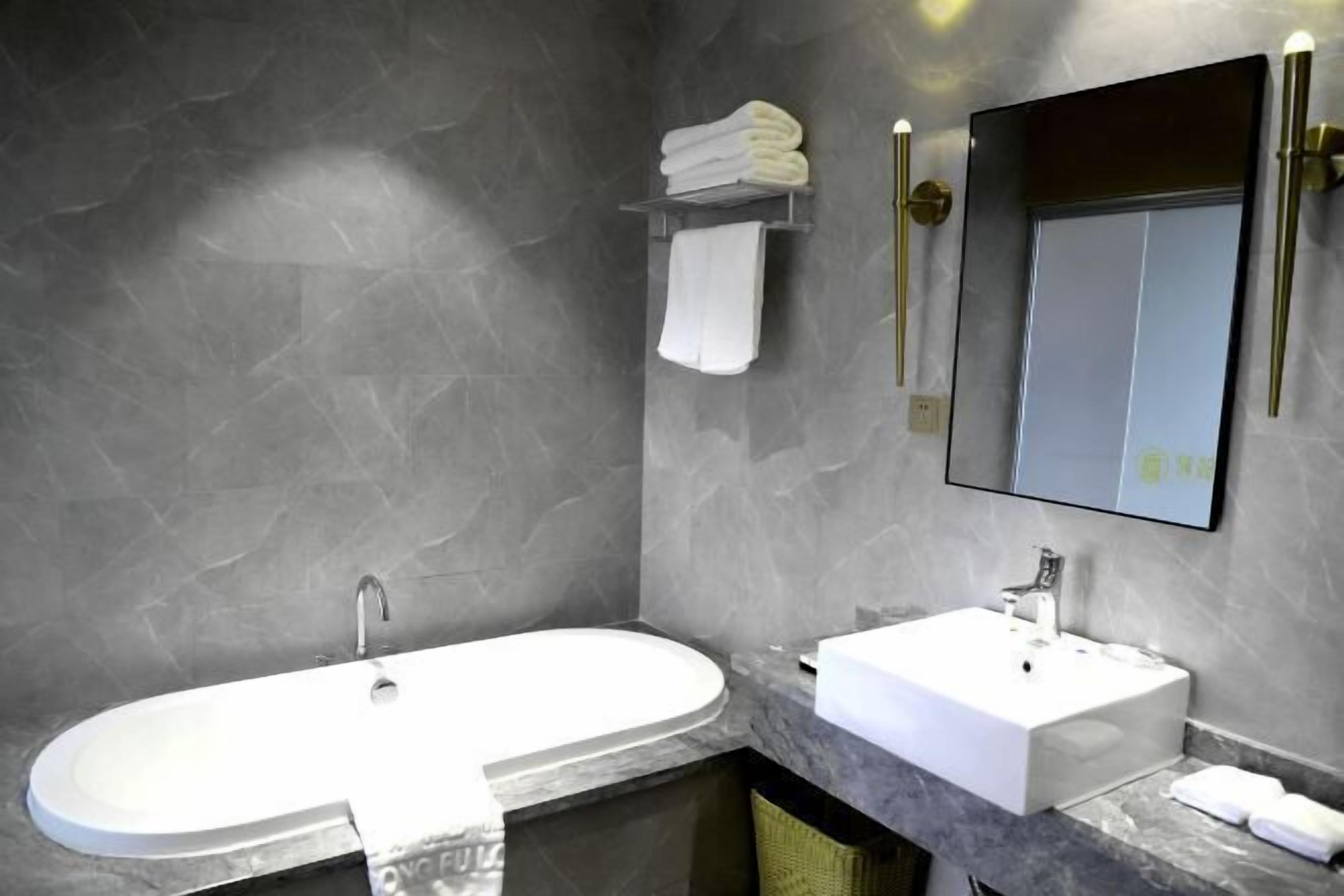 Une salle de bain moderne avec une grande baignoire ovale, un lavabo blanc et un miroir au-dessus du lavabo.
