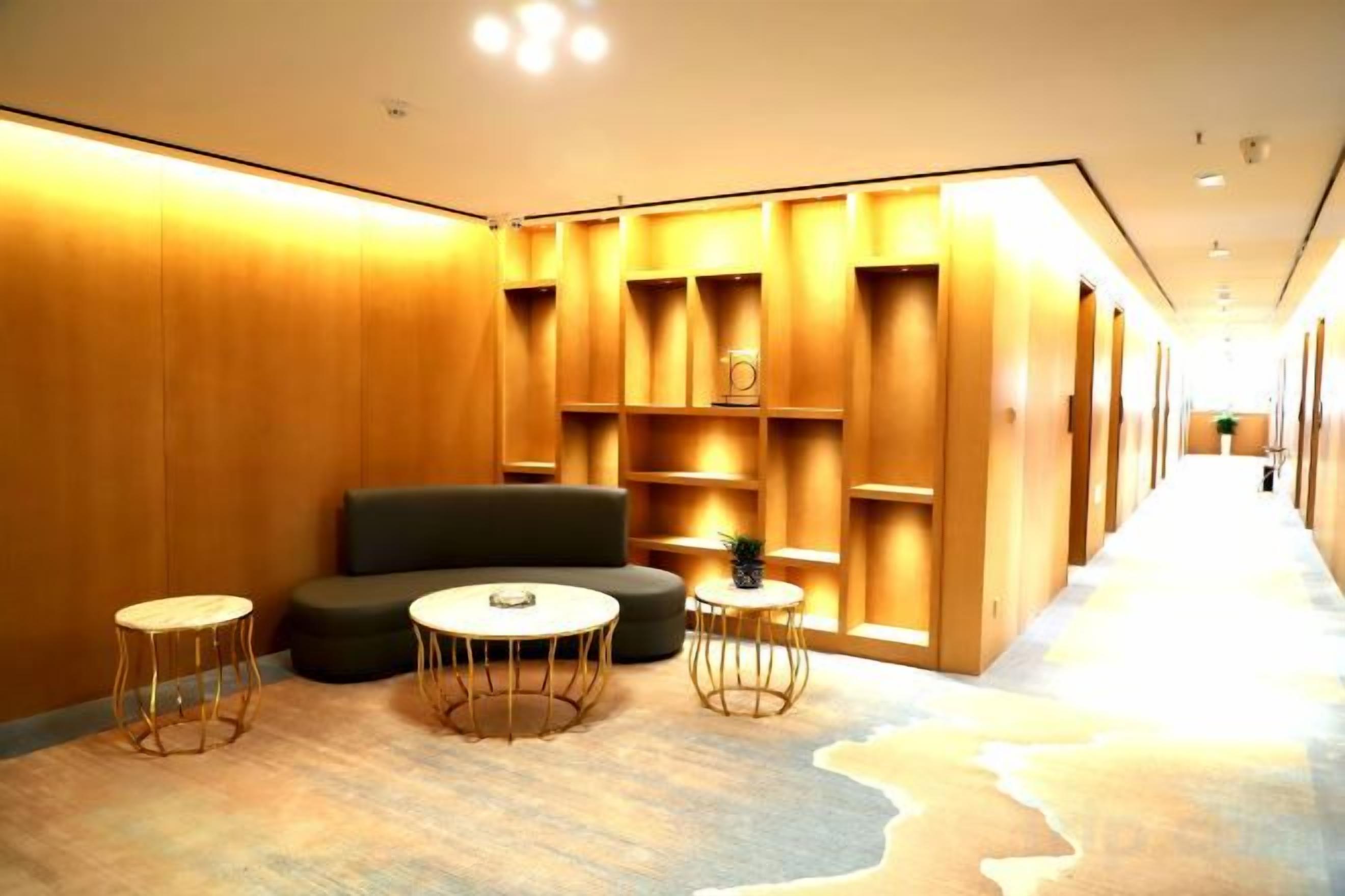 Een hotel lobby met een bank, twee ronde tafels en ingebouwde planken.