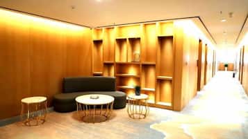 A hotel lobby with a sofa, two round tables, and built-in shelving.