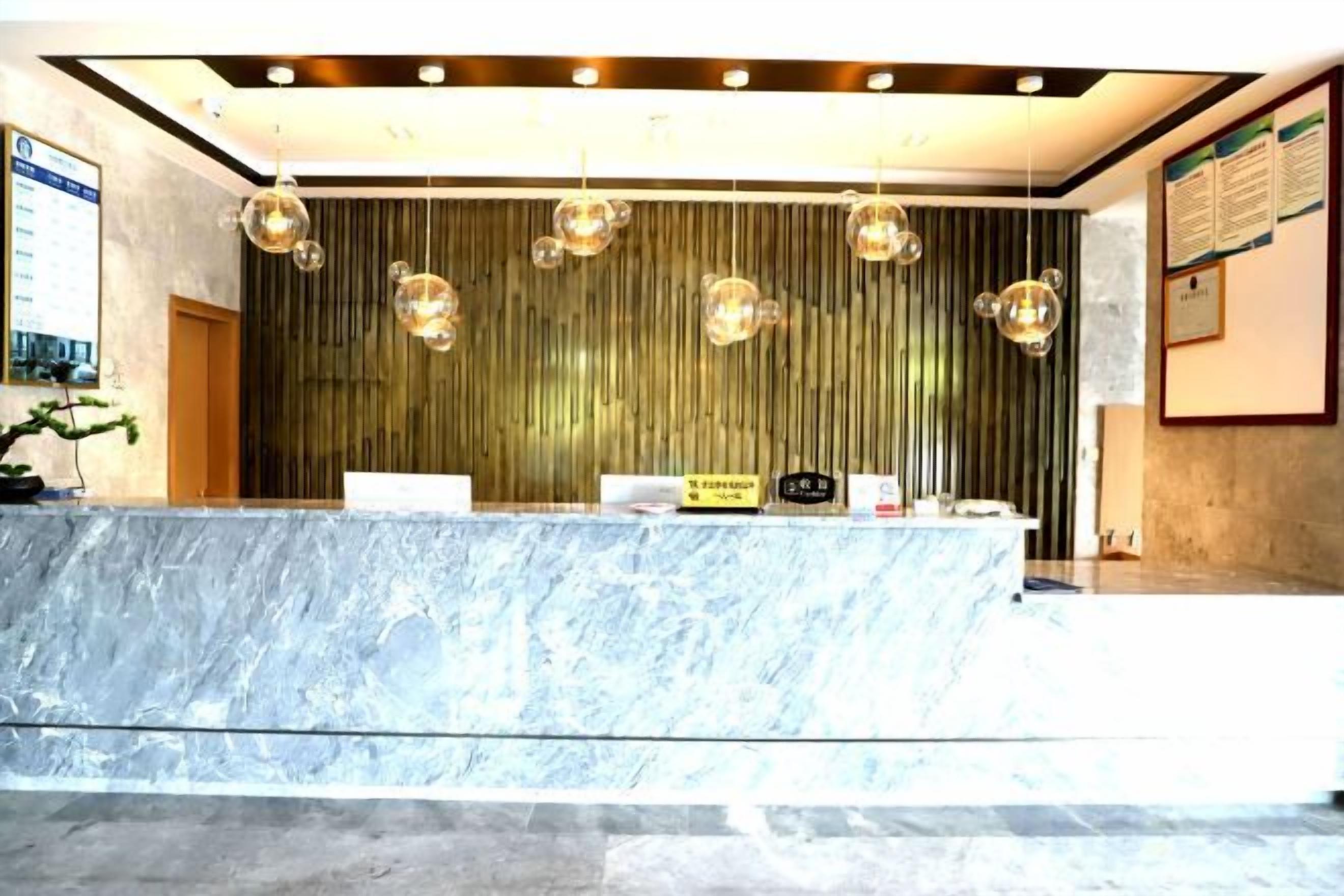 A reception area with a marble counter, hanging pendant lights, and a vertical wooden panel wall.