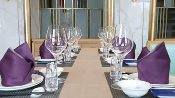 Una mesa de comedor preparada con varios vasos de vino, platos y servilletas dobladas.