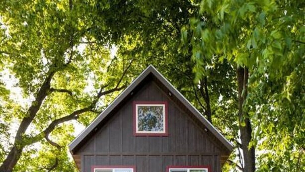 A wooden cabin with a balcony, large windows, and a swing set. - Marion Lake Tree House (Perham)