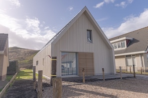 Un bâtiment moderne, de plain-pied, doté d’un toit en pente et d’une grande porte-fenêtre coulissante.