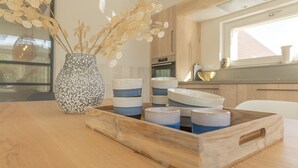 Une table en bois sur laquelle se trouvent un vase en céramique et un plateau avec des bols et des tasses.