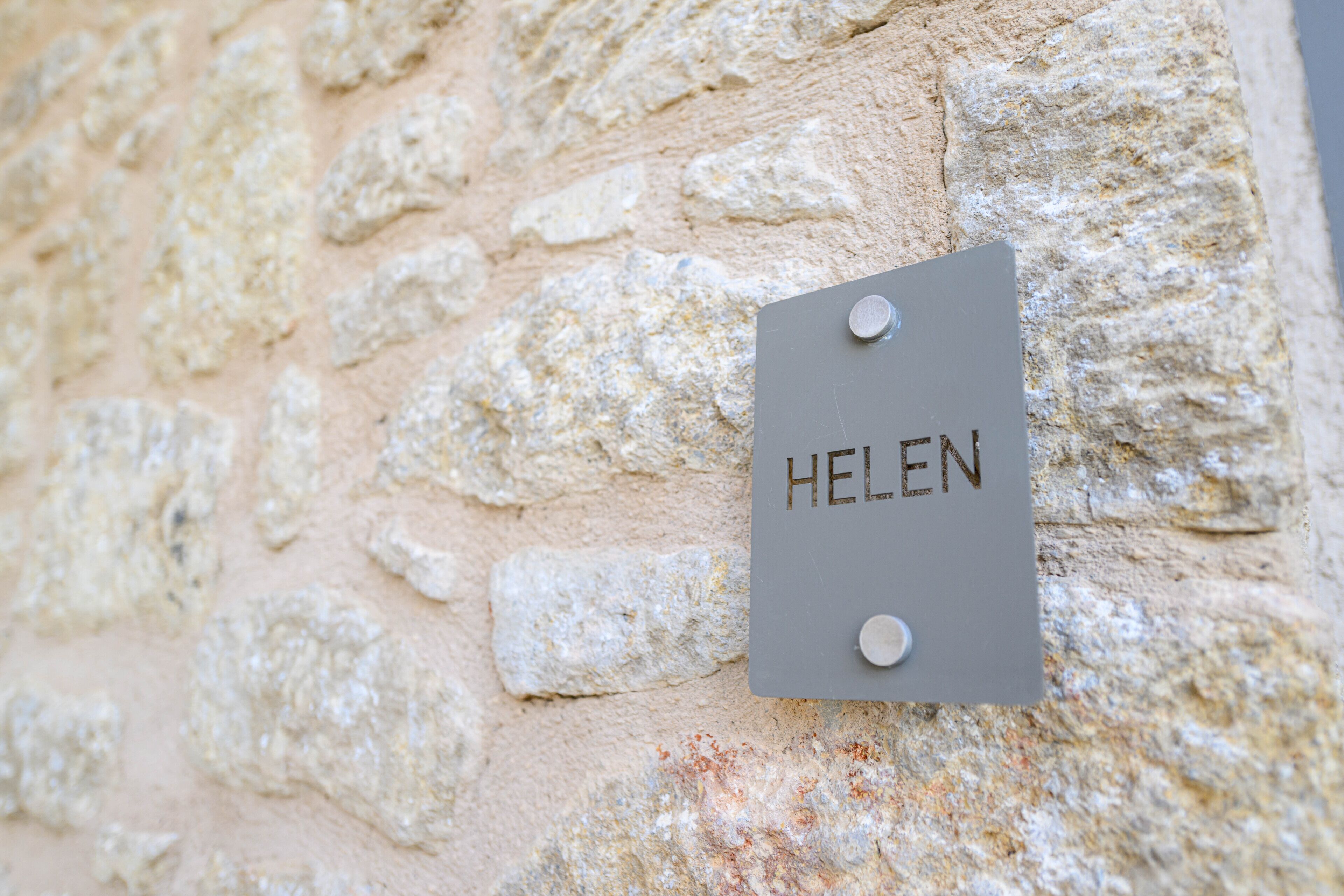 A sign with the name "HELEN" on a stone wall.
