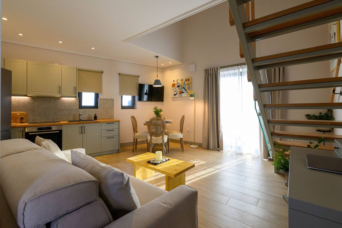 Een modern appartement met een woongedeelte, keuken, eethoek en een trap.