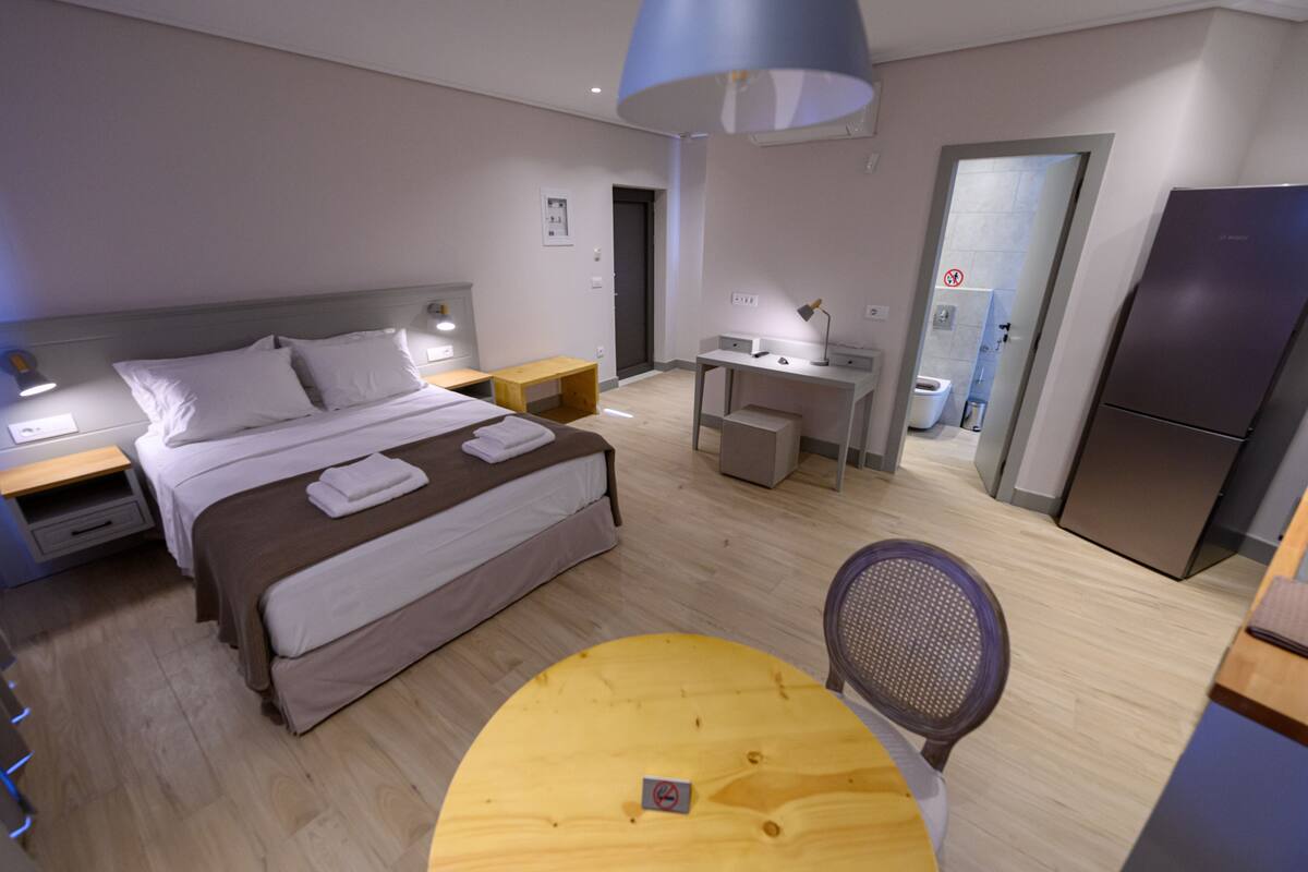 Een moderne hotelkamer met een bed, nachtkastjes, een bureau, een stoel en een koelkast.
