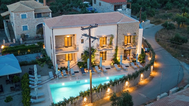 A multi-story building with a swimming pool, surrounded by a landscaped garden and a road. - Kannas Mani-Luxury Suites- Adults friendly 14+ (West Mani)