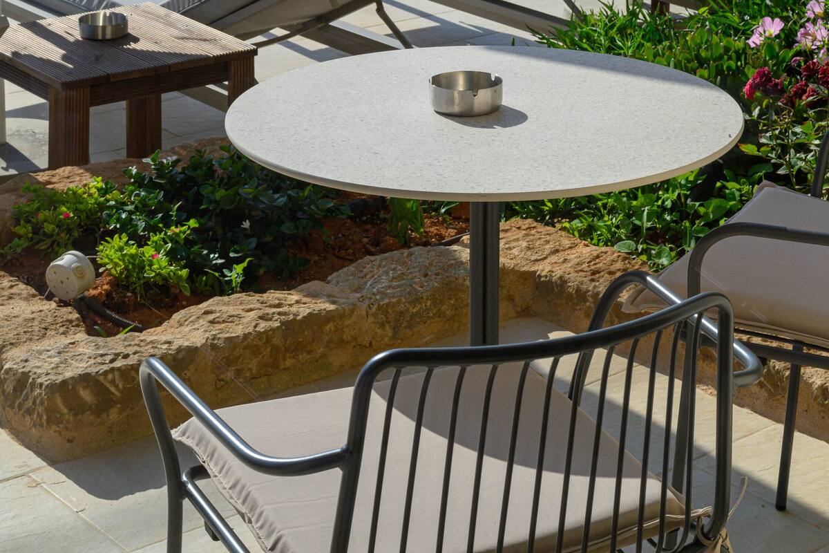 Een zwembadgedeelte met ligbedden, een tafel en een kleine ronde tafel met een metalen kom.