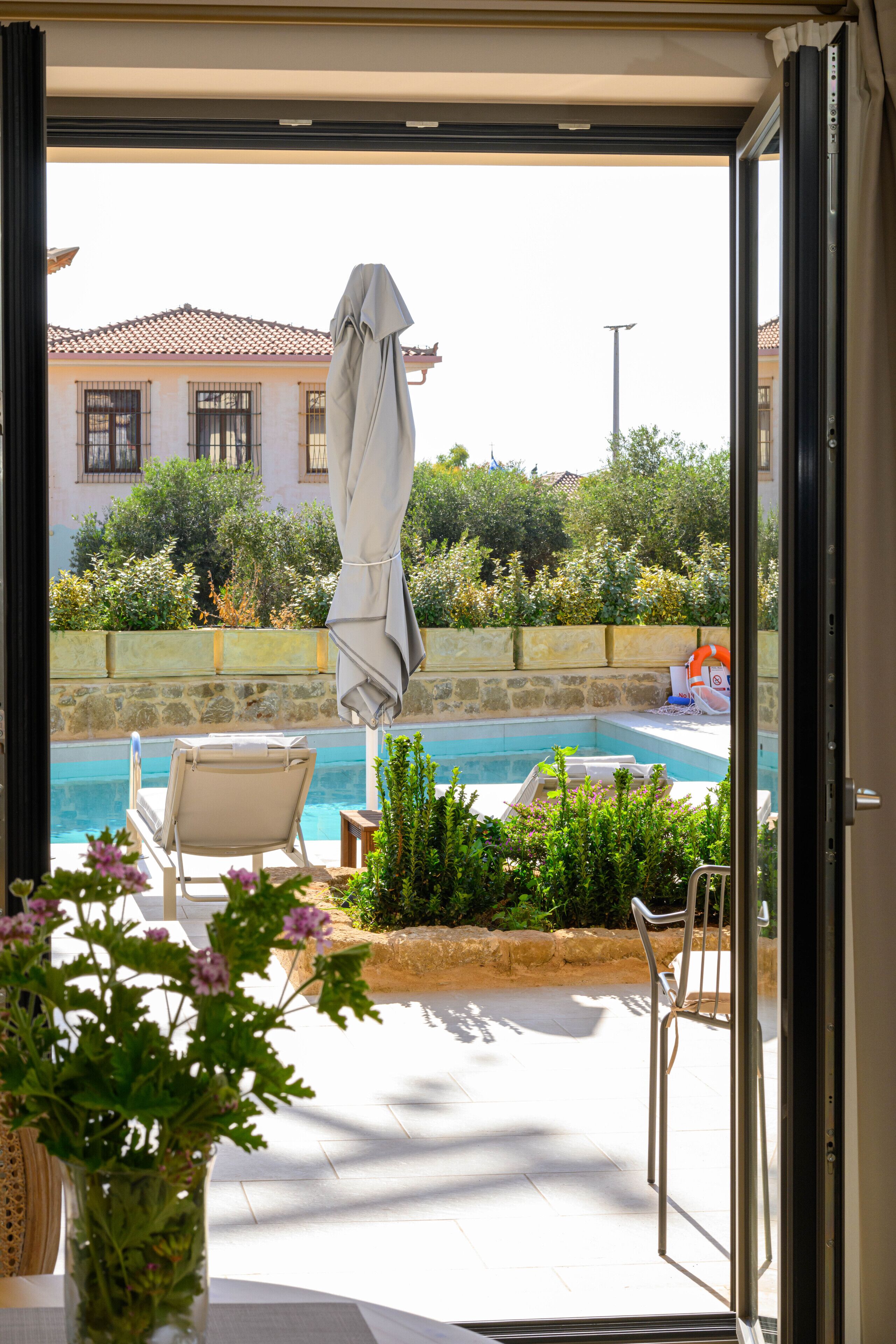 Un área junto a la piscina con una silla, una mesa y una planta en maceta.