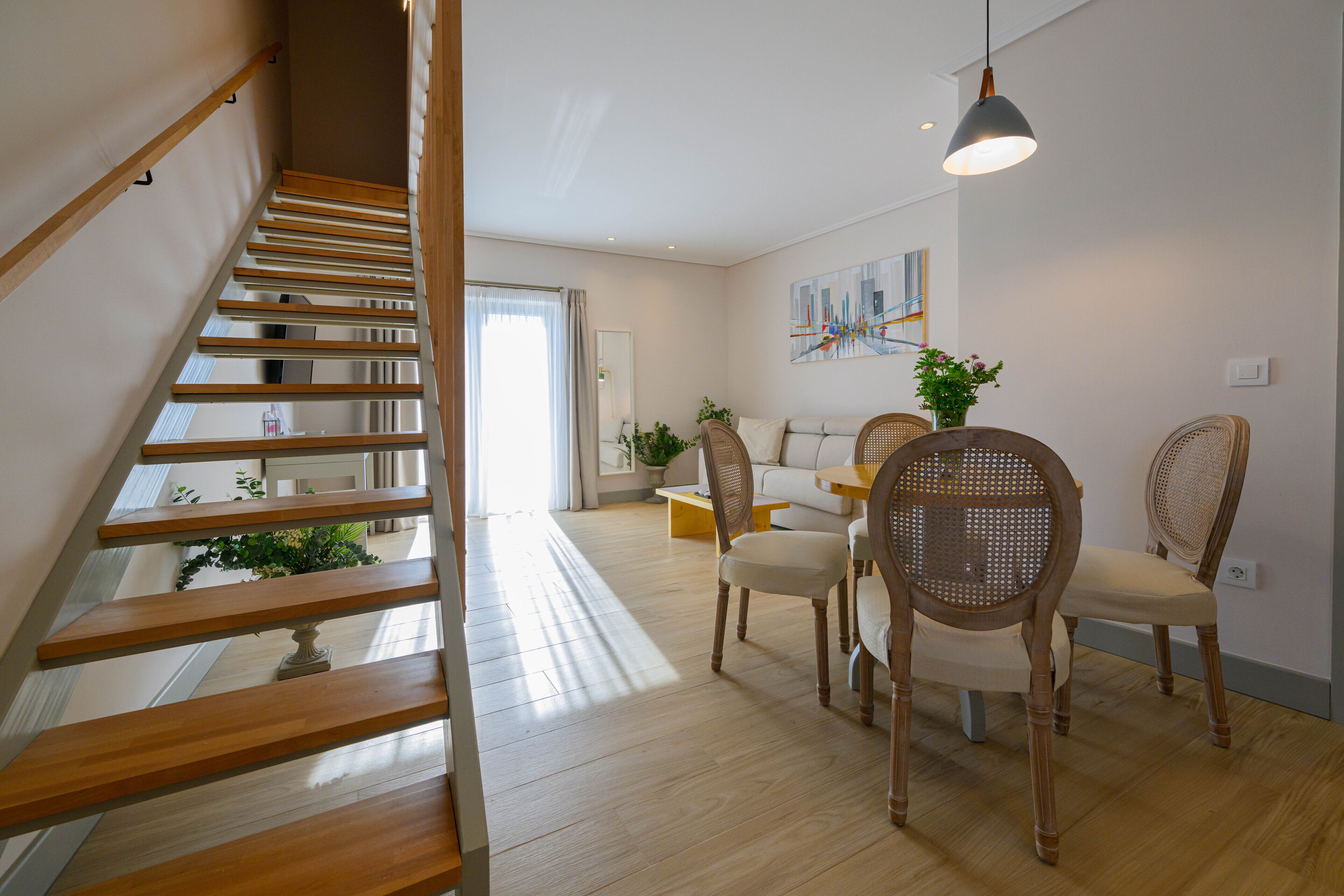 Een trap die leidt naar een eetgedeelte met houten stoelen en een tafel.