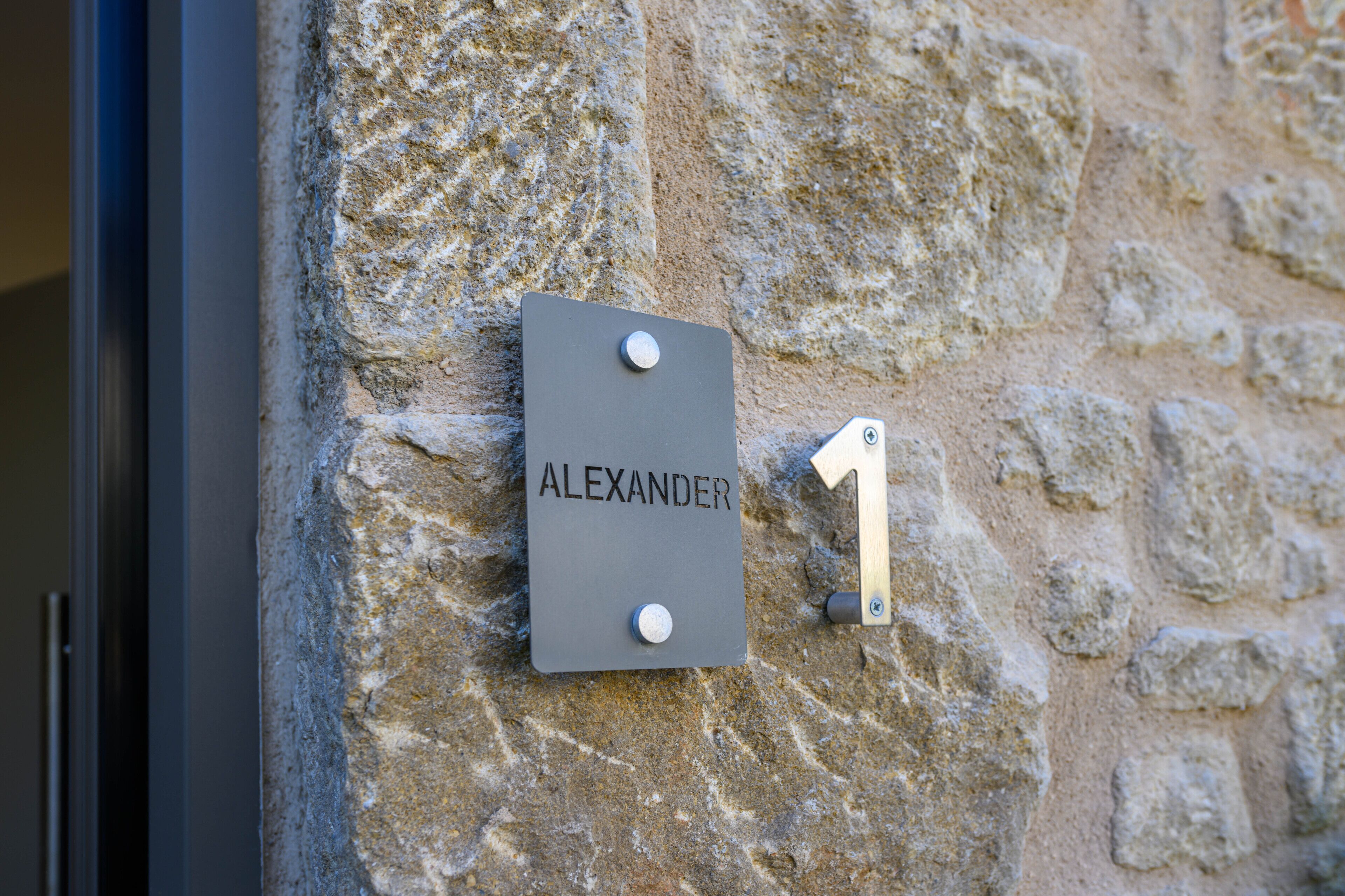 A stone wall with a sign reading "ALEXANDER 1".