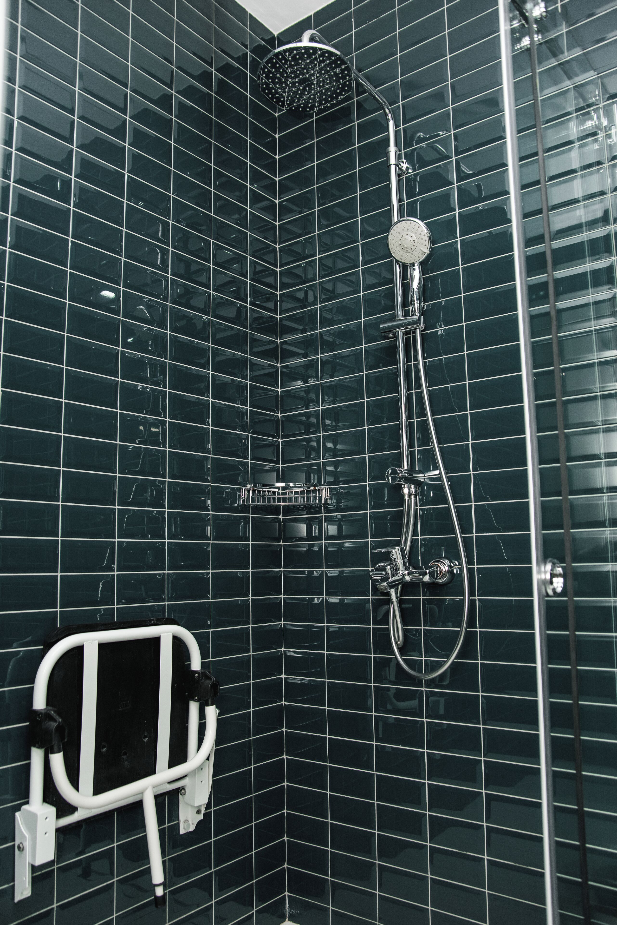 A modern bathroom with a glass shower enclosure, a handheld showerhead, and a handheld shower attachment.