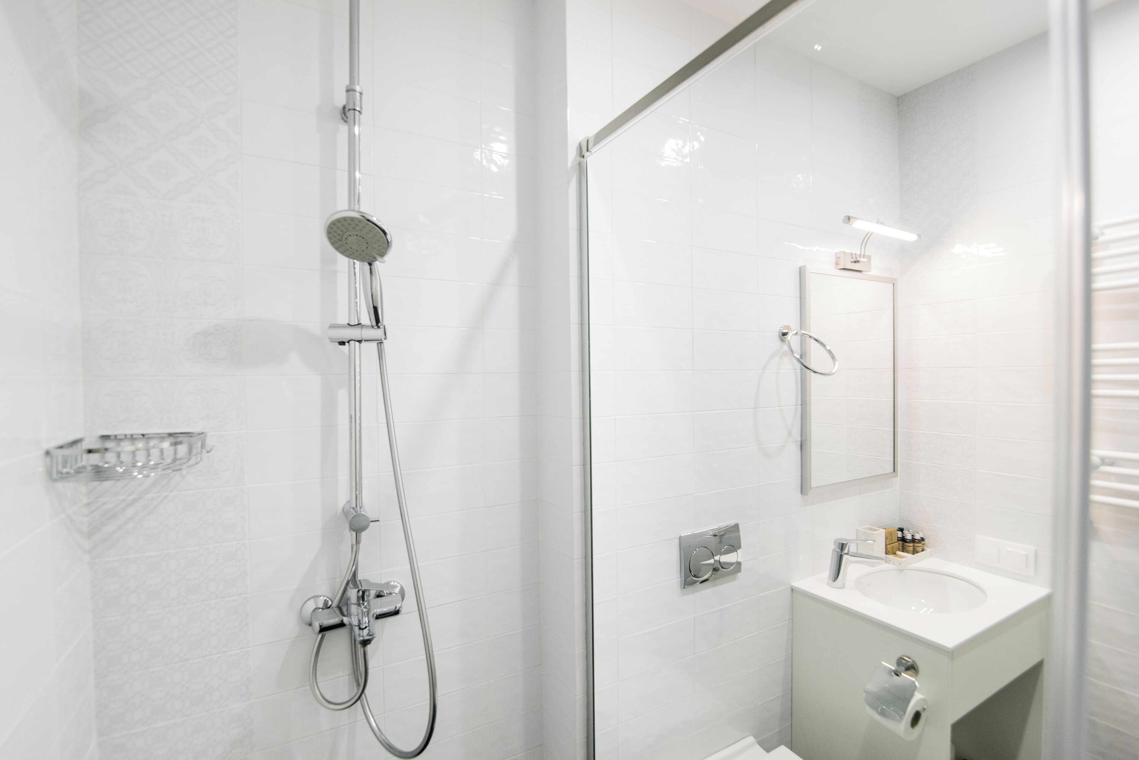 A modern bathroom with a glass-enclosed shower, a white sink, and a mirror above the sink.