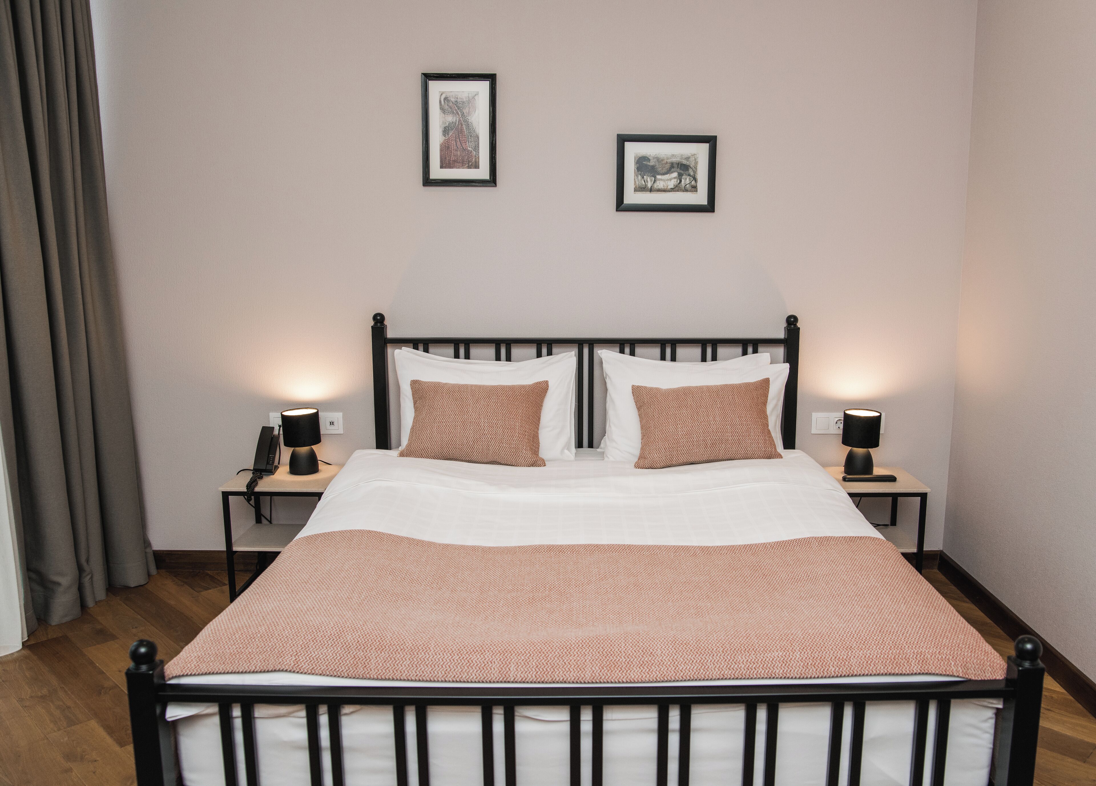 A neatly made bed with a patterned bedspread, two pillows, and two bedside lamps on nightstands.