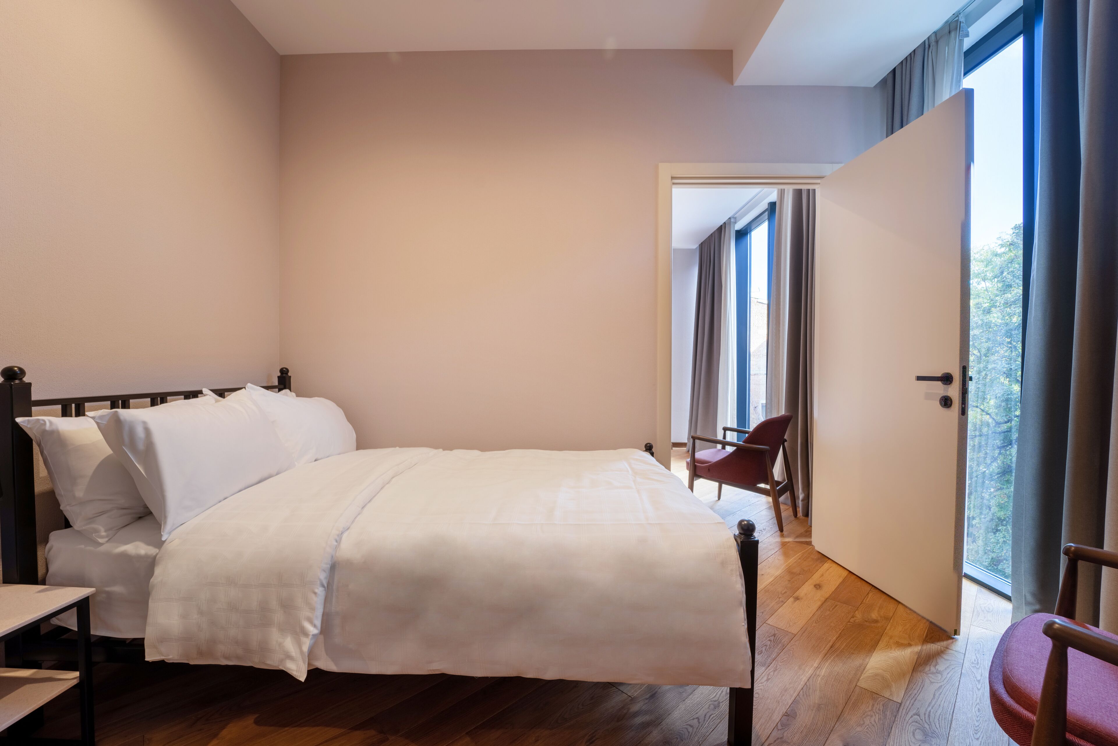 Un dormitorio con cama, una silla y una puerta que da a un balcón.