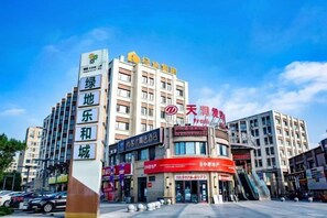 A multi-story hotel with a prominent sign, a central entrance with a red awning, and a clear sky. - Shankee Hotel (Shanghai Jinshan Wanda) (Shanghai)