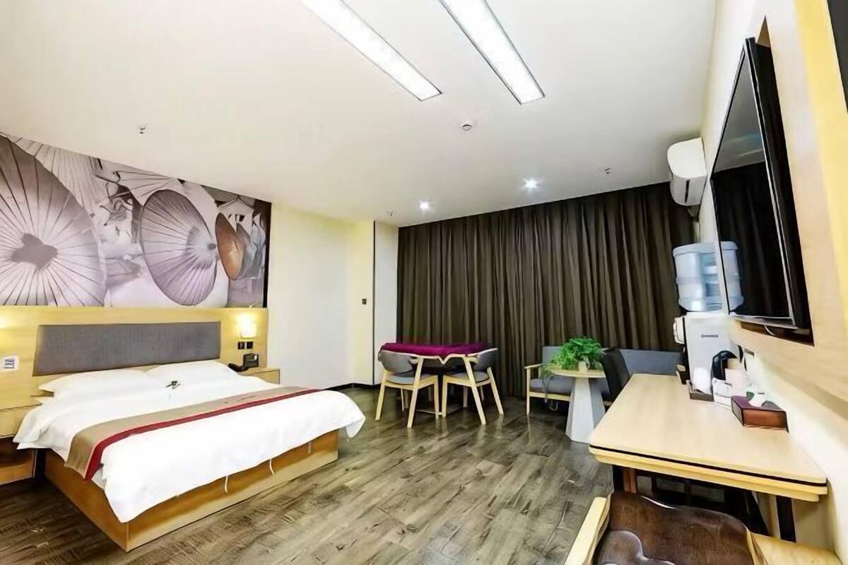 A hotel room with a bed, a desk, a chair, a water dispenser, and a large mirror.