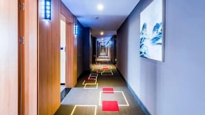 Passadís d'hotel amb portes de fusta, un mur blau i un quadre amb marc.