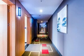 A hotel hallway with wooden doors, a blue wall, and a framed picture. - Shankee Hotel (Shanghai Jinshan Wanda) (Shanghai)