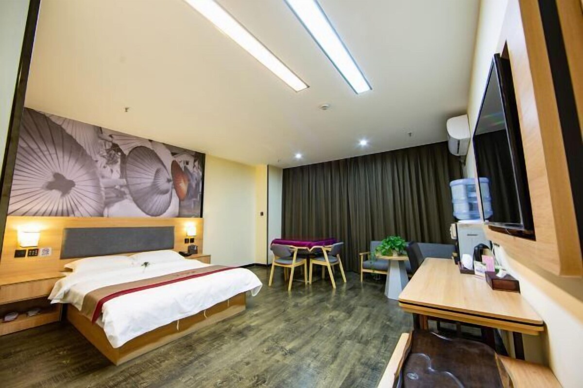 A hotel room with a bed, desk, chairs, and a large wall mural.