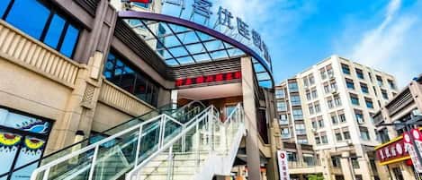 A hotel entrance with a curved glass facade, a staircase, and a clear sky.