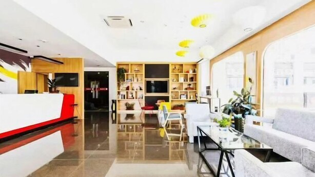 Un vestíbul d'hotel modern amb taulell de recepció, zona de seients i grans finestres.