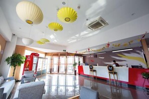 A modern hotel lobby with a reception desk, seating area, and decorative ceiling lights. - Shankee Hotel (Shanghai Jinshan Wanda) (Shanghai)
