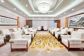 A hotel conference room with rows of white sofas, a patterned carpet, and a chandelier. - Lian Yun Hotel (Kunming)