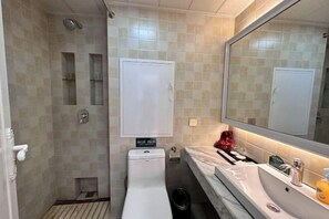 A bathroom with a shower, toilet, sink, and mirror. - Lian Yun Hotel (Kunming)